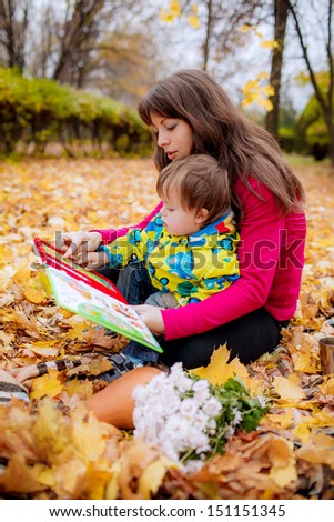 Mom and son  reading a book in the autumn garden