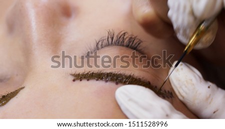 Cosmetologist applying permanent tattooing of eyebrows in beauty salon, Microblading procedure