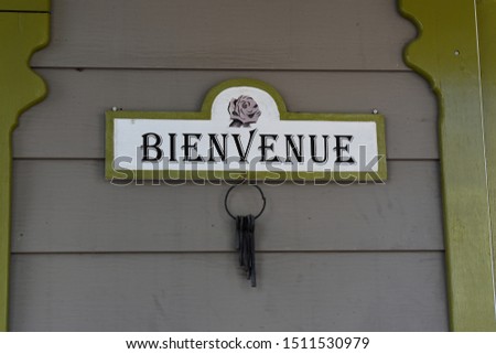 Picture of welcome sign (bienvenue in french) on a door with old keys hanging.