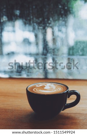 Hot coffee cup on wooden table by the windows in rainy day.