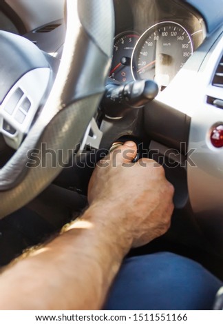 Selective focus male hand winds up the car ignition key, car driving and dashboard. Travel Background - Image