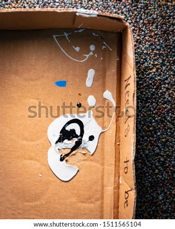 Spilled paint drops in cardboard box