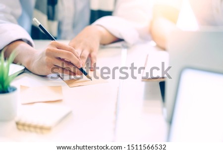 Closeup female hand writing note with black pencil while sitting at office desk, copy space.