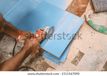 worker cutting a tile floor at construction site
