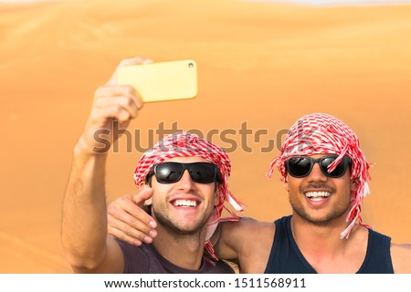 Happy male friends taking a selfie together in the desert. Two travelers. 