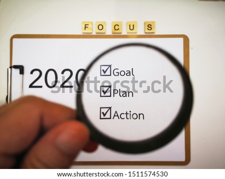Businessmen make checklists for January 2020 , word in picture is  "GOAL" "PLAN" "ACTION" , holding the magnifying glass ,business concept