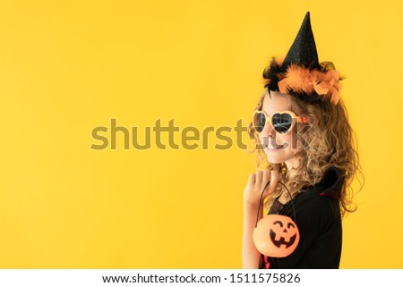 Portrait of beautiful girl dressed witch costume against yellow background. Halloween holidays concept