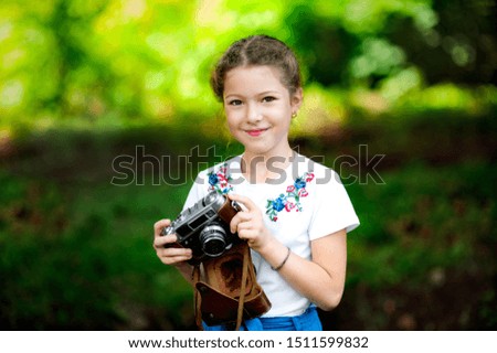 Beautiful smiling girl holding a camera outdoors