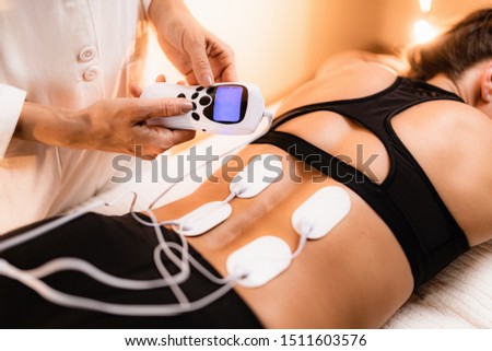 Lower Back Physical Therapy with TENS Electrode Pads, Transcutaneous Electrical Nerve Stimulation. Electrodes onto Patient's Lower Back Royalty-Free Stock Photo #1511603576
