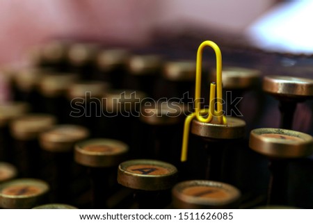 Yellow paper clip sitting on typewriter, close up. Vintage typewriter and paperclips.