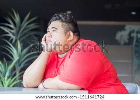 Picture of overweight man looks pensive while sitting on the chair