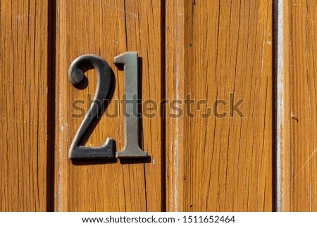 House number 21 on a varnished wooden front door