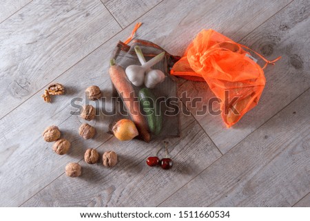eco-friendly handbags, on a light surface with vegetables, nuts, garlic, cucumber, cherry 