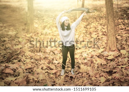 Picture of attractive young woman looks happy while dancing in the autumn park with dried autumn foliage