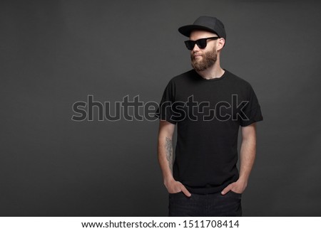 Hipster handsome male model with beard wearing black blank t-shirt with space for your logo or design Royalty-Free Stock Photo #1511708414
