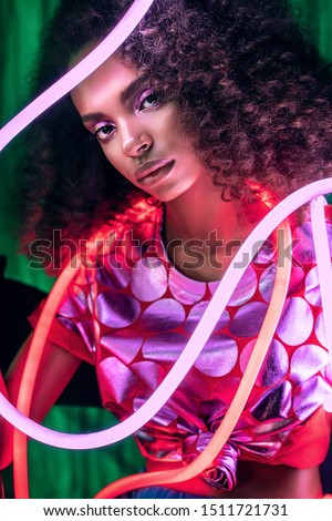Portrait of beautiful african woman with red and pink neon light. Woman with afro hairstyle. Pink and red flexible neon light tubes