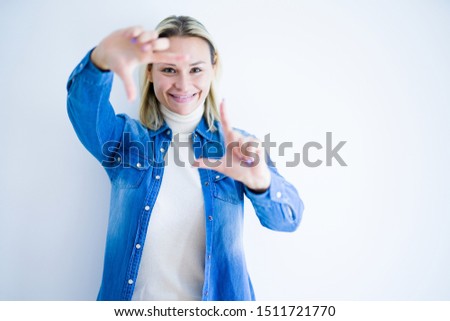 Young beautiful woman wearing denim shirt standing over isolated white background smiling making frame with hands and fingers with happy face. Creativity and photography concept.