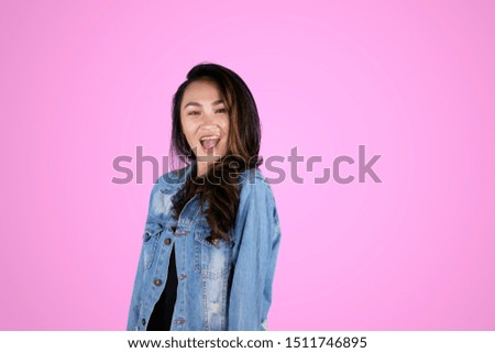 Picture of pretty girl smiling at the camera while standing in the studio with purple color background