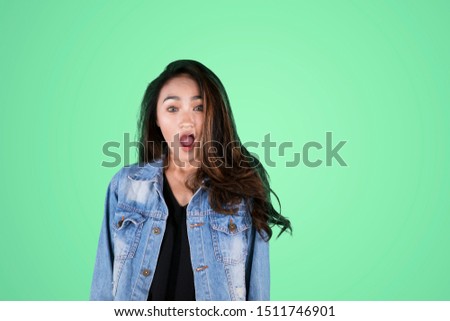 Picture of pretty girl wearing a jacket while standing with shocked expression in the studio