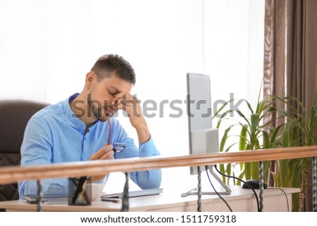 Tired businessman sitting at table in office
