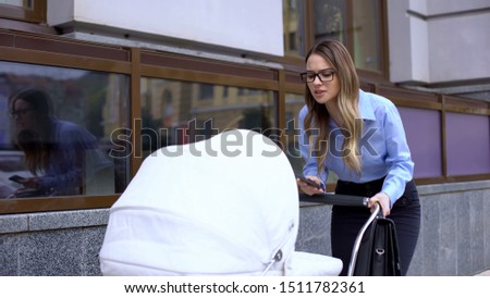 Irritated female manager with baby pram trying to work and calm infant, stress