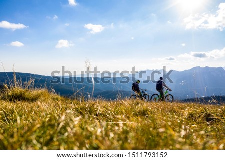 Aerial view. Epic shot of two mountain bikers on top of the mountain looking down the valley. Aerial shot of mountain biker on the top looking at amazing view in the autumn. mountain bike. bycicle Royalty-Free Stock Photo #1511793152