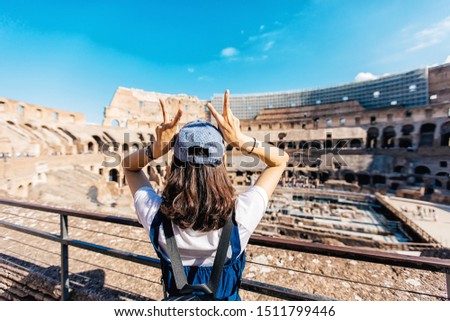 Young Girl looks at Colosseum, Rome, Italy. Colosseum (Coliseum) is the main tourist attraction of Rome. Adult girl visits the Rome landmark in summer. People travel across sunny Rome on vacation.