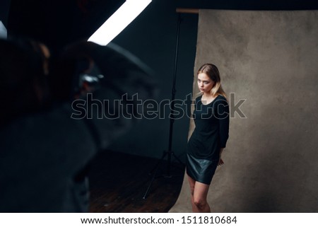 female model in dark clothes posing for photographers indoors                   