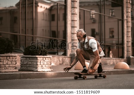 Adult bearded man portrait with longboard. Stylish model in casual clothes ride skateboard on city street background. Outdoors style. Sport lifestyle Royalty-Free Stock Photo #1511819609