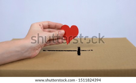 Female hand putting red heart sign church donation box, religious mercy, charity