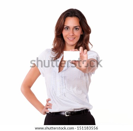A portrait of a beautiful hispanic young woman on white blouse holding a blank business card while looking at you on isolated background - copyspace