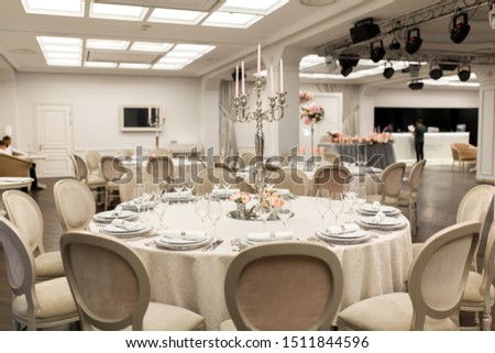 The white round banquet table in the restaurant is decorated with fresh flowers. Stylish event decor.