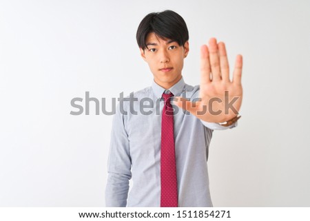 Chinese businessman wearing elegant tie standing over isolated white background doing stop sing with palm of the hand. Warning expression with negative and serious gesture on the face.