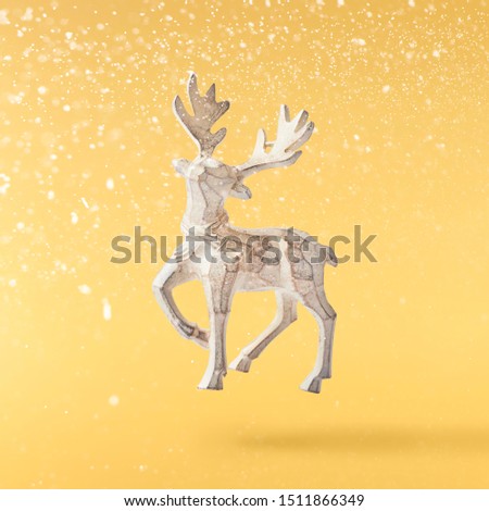 Christmas card conception. Christmas  toy deer decoration falling in the air on yellow background. Levitation concept. High resolution image