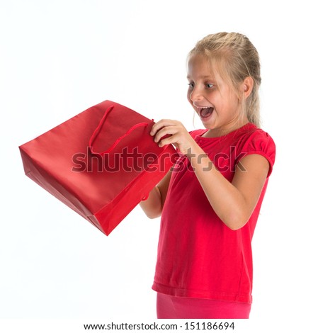 Excited little girl looking inside shopping bag on a white background