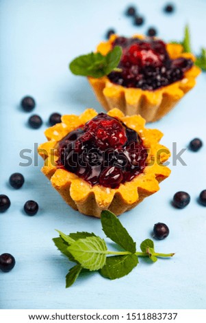 Small berry cake and ripe berries on a blue wooden background. Delicious dessert. 