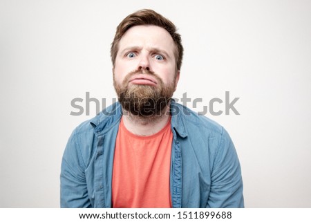Funny bearded man with pouting lips, a compassionate and tired look, makes a silly grimace after a whole working day. Isolated on a white background. Royalty-Free Stock Photo #1511899688