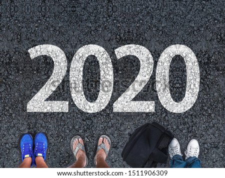  happy new year 2020. people legs standing on asphalt road next to number 2020