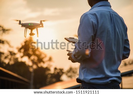 Man operating a drone with remote control, drone pilotage at sunset - Image