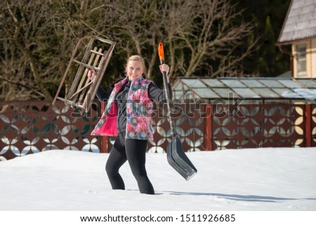 Beautiful girl with a shovel and sled in the snow