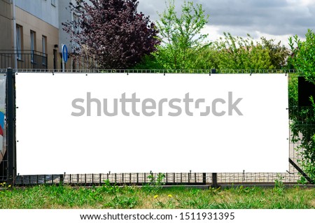 Blank white advertising banner mounted on the fence against office building.