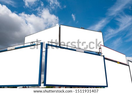 Group of the blank white advertising billboards in the city against blue sky.