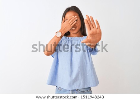 Young chinese woman wearing blue t-shirt and glasses over isolated white background covering eyes with hands and doing stop gesture with sad and fear expression. Embarrassed and negative concept.