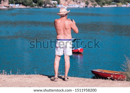 Back view of older man take a photo at the beautiful view at the lake.