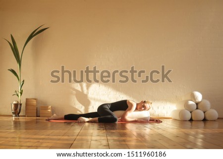 Woman practiving restorative yoga in a beautiful studio Royalty-Free Stock Photo #1511960186