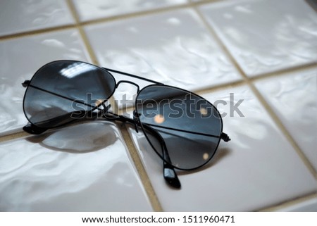 Aviator sunglasses. Black glasses in the form of a droplet on white tiles. Classic black Sunglasses.
