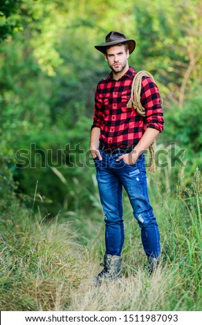 American cowboy. Lasso tied wrapped. Western life. Man cowboy nature background. Man wearing hat hold rope. Ranch owner. attle breeding concept. Cowboy at countryside. Ranch occupations. Lasso tool. Royalty-Free Stock Photo #1511987093