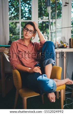 Vertical Portrait of Young Beautiful Female Graphic Designer Sitting at Modern Office Space with Big Windows Enjoying Work