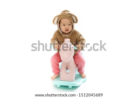 Cute baby riding a wooden horse with a white background              