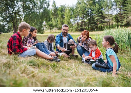Group of school children with teacher and windmill model on field trip in nature. Royalty-Free Stock Photo #1512050594